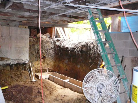 1997 Mercury Grand Marquis - This image shows a construction site with a dug-out foundation, wooden forms for concrete, a green ladder, and a fan. The scene appears to…