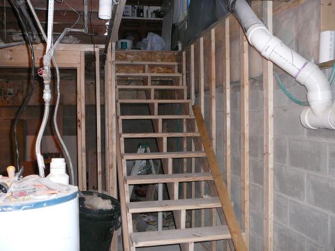 1997 Mercury Grand Marquis - A basement scene shows unfinished construction with a wooden staircase, plumbing pipes, and a water heater.
