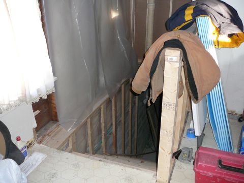 1997 Mercury Grand Marquis - This unfinished basement staircase is covered with plastic sheeting and has jackets draped over the railing.