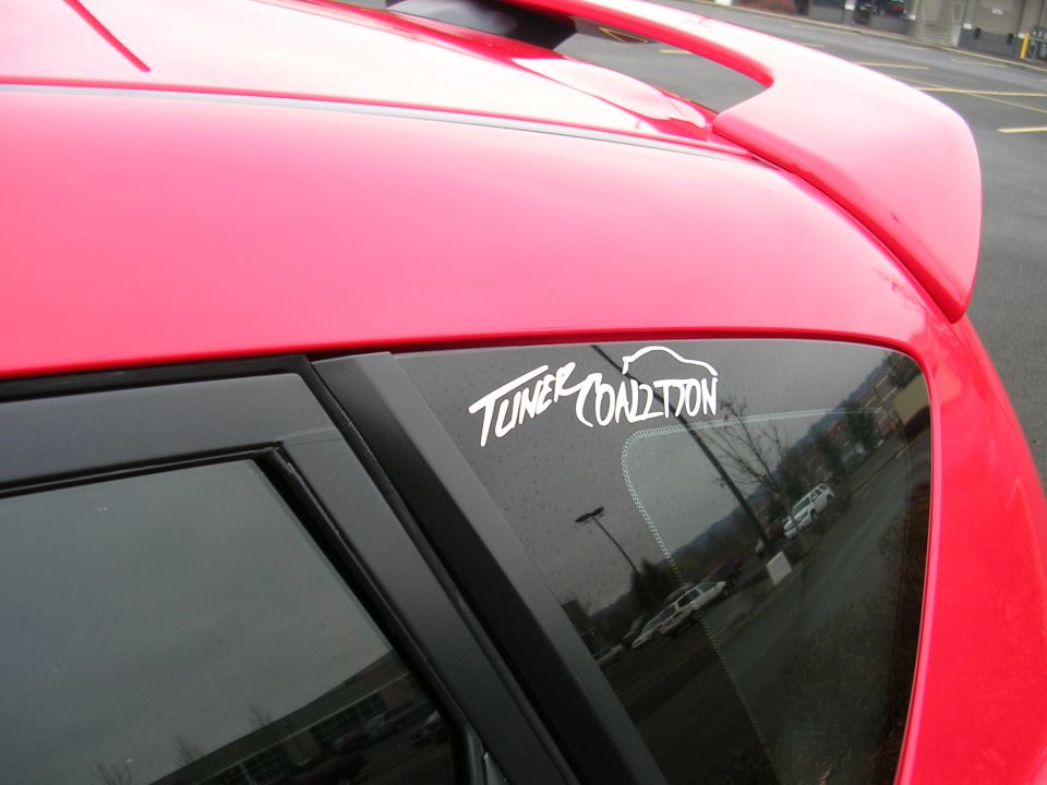 White "TUNER COALITION" sticker on the rear window of a red Mazda 3.