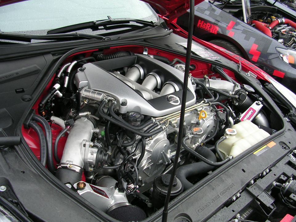 Modified V6 twin-turbo engine bay with aftermarket intake and Perrin strut brace.