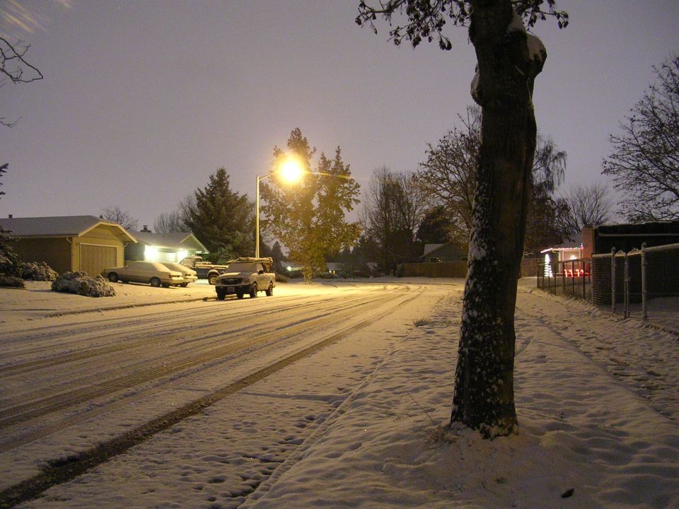 White pickup truck parked on a snowy street at night.