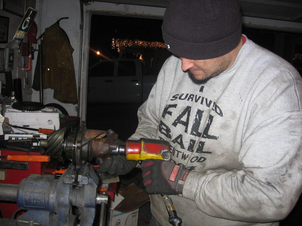 Man using a pneumatic impact wrench on a pinion held in a vise