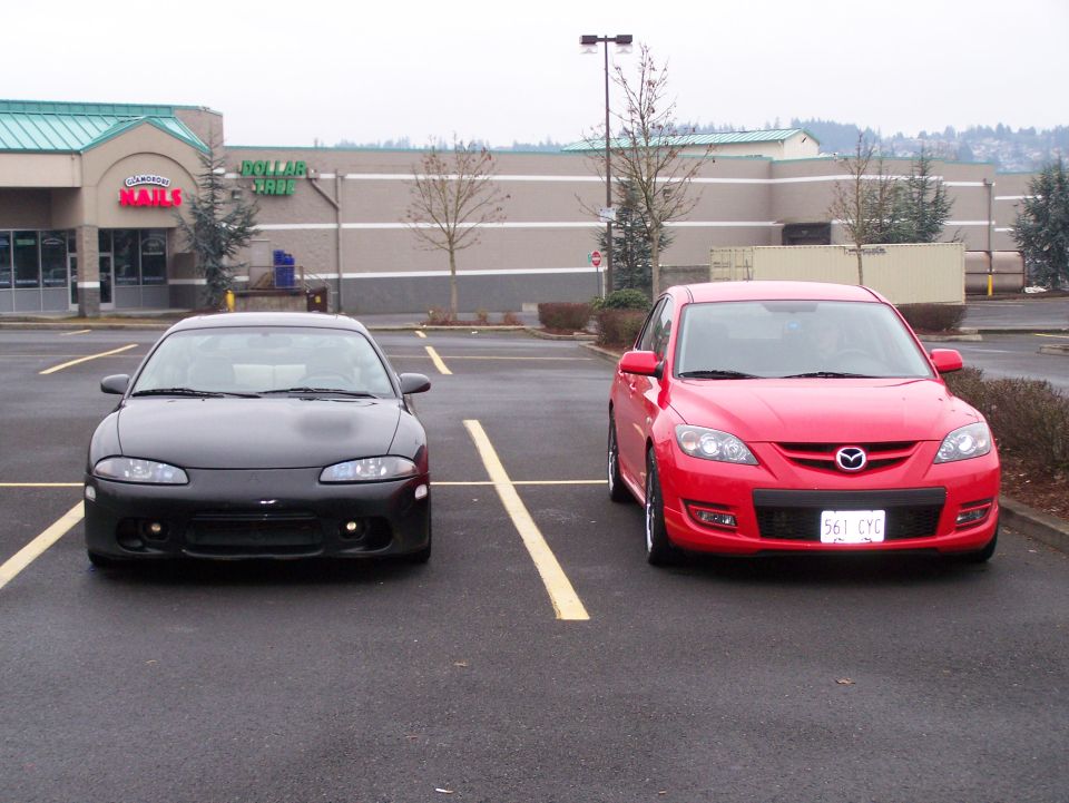 Black Mitsubishi Eclipse and red Mazda 3 parked in a lot.