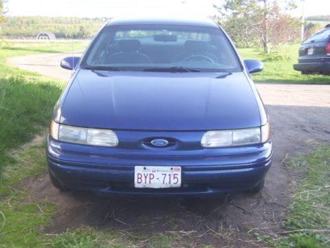 1995 Ford Taurus - 1995 Ford Taurus sedan parked outdoors, showing its front grille and headlights.