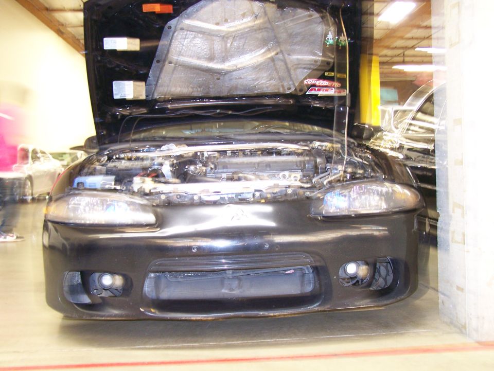 Front view of a black Mitsubishi Eclipse with hood open, showing the engine.