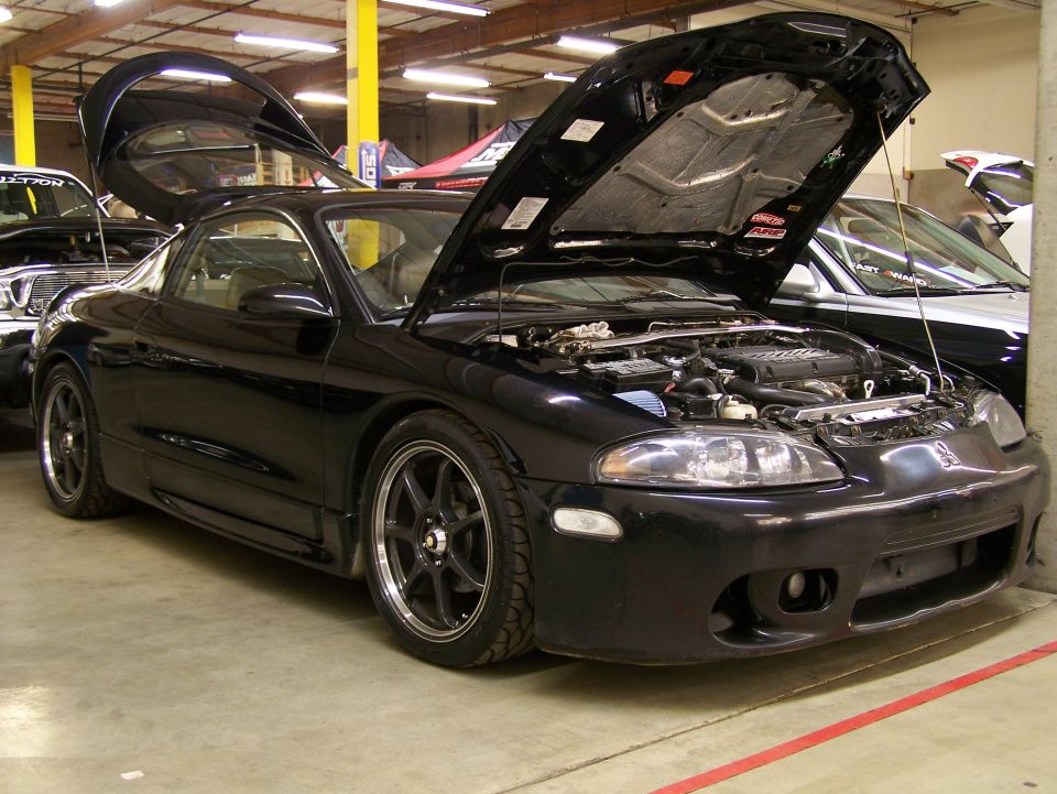 Black coupe with hood and doors open, showing engine bay.