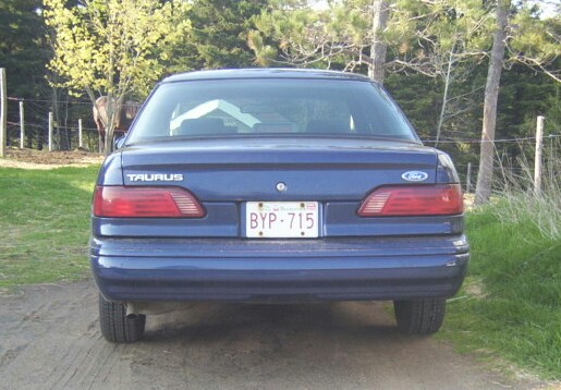 Rear view of a blue Ford Taurus with license plate BYP-715 parked outdoors