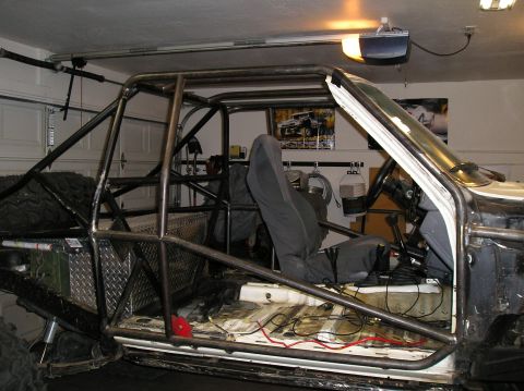 1986 Toyota Hilux - The interior of a heavily modified Toyota Hilux pickup truck is shown, featuring a custom roll cage, racing seat, and exposed wiring. The v…