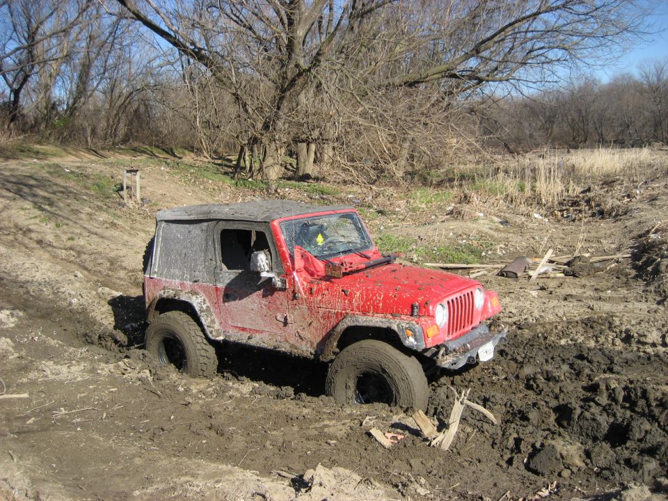 Red Jeep Wrangler stuck in mud