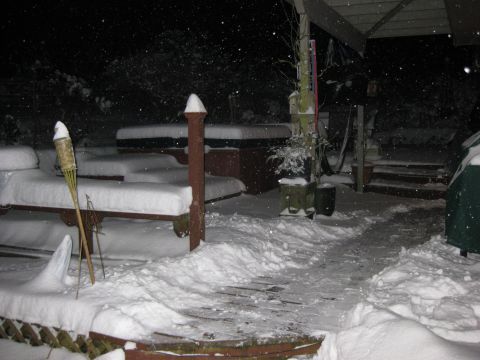 1979 Ford Bronco - A snowy backyard scene at night with a covered hot tub and outdoor furniture.