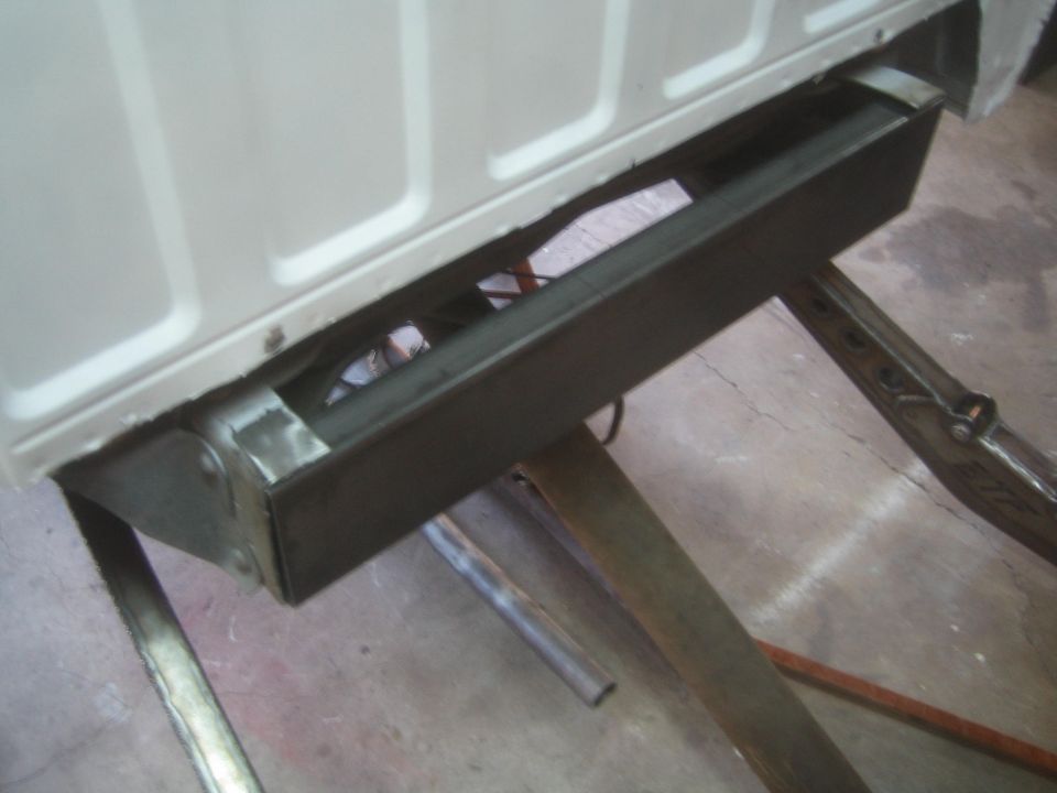 Fabricated steel crossmember welded under a white vehicle body panel