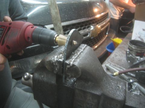 1990 Ford Bronco - Photograph of drilling a metal part in a vise, not a technical document.