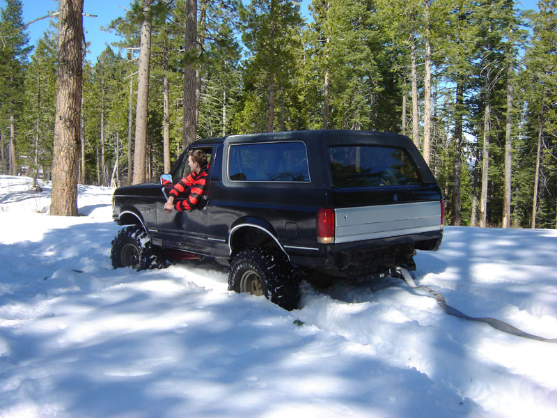 Black Ford Bronco in snowy forest with child looking out window