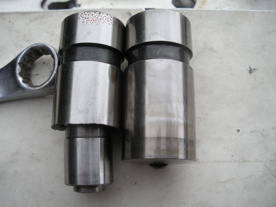 Two metal cylindrical parts and a wrench on a surface.