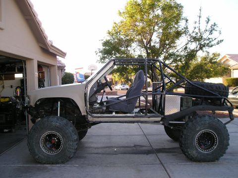 1986 Toyota Hilux - A custom-built off-road vehicle, likely a modified Toyota Hilux, is parked in a driveway with a garage in the background. The vehicle featu…