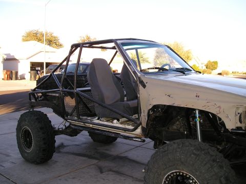 1986 Toyota Hilux - A custom-built off-road vehicle, likely a modified pickup truck, is parked on a paved surface in front of a residential building. The vehic…