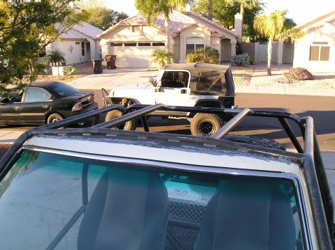1986 Toyota Hilux - A white Jeep Wrangler with a black soft top is parked on a residential street next to a black sedan. The foreground shows the interior of a…