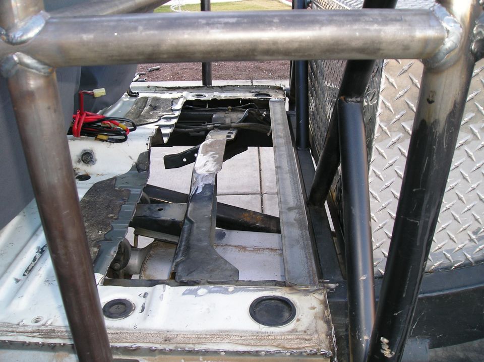 Interior view of a vehicle chassis with a roll cage and exposed wiring.