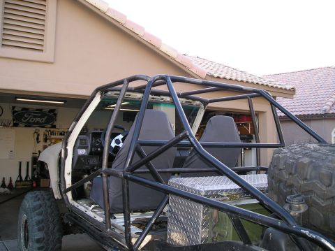 1986 Toyota Hilux - A custom-built off-road vehicle, likely a Toyota Hilux, is shown partially assembled in a garage. The vehicle features a prominent roll cag…