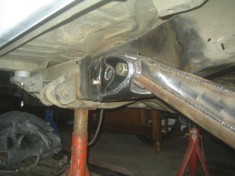 1990 Ford Bronco - Photograph of welded suspension link and bracket under a vehicle, not a technical document.