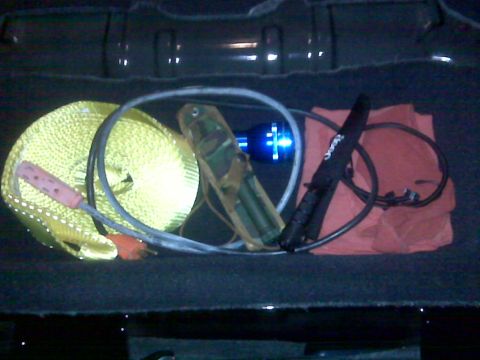 2008 Jeep Wrangler - A collection of items including a yellow tow strap, a blue flashlight, a knife with a Jeep logo, and a red cloth are arranged inside the tr…