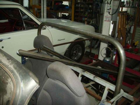 1969 MINI Cooper - A roll cage and car seats are visible inside a vehicle undergoing work in a cluttered garage setting.