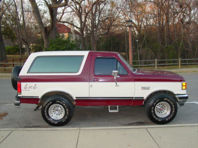 Side view of a two-tone red and white 1988 Ford Bronco with 4x4 badging