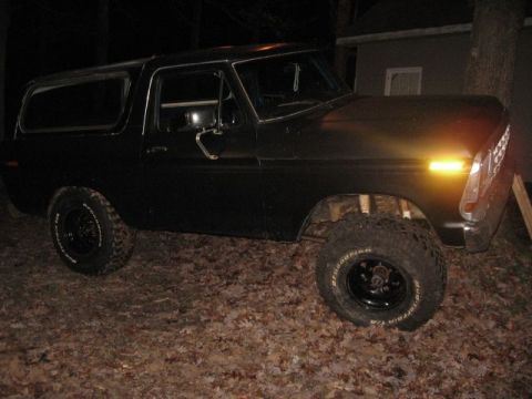 1978 Ford Bronco - Black 1978 Ford Bronco parked on leaf-covered ground at night.