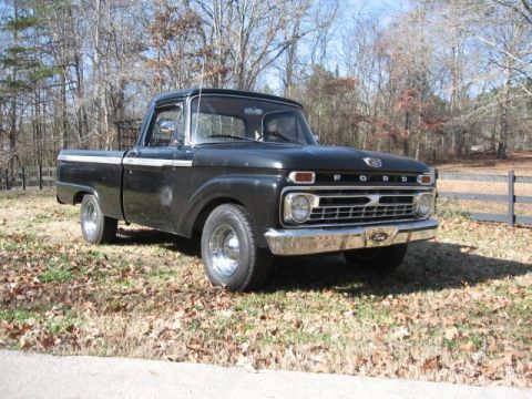 1966 Ford F-100 - This classic Ford F-100 pickup truck is shown from a three-quarter front view, parked outdoors on a sunny day.