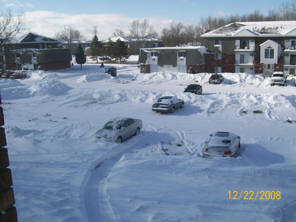Several cars partially buried in deep snow drifts in a parking lot