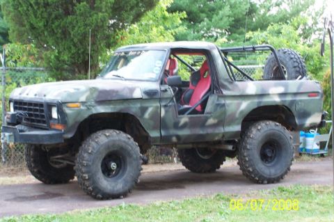 1979 Ford Bronco - This modified SUV features a camouflage paint scheme, racing seats, and a roll cage, indicating it is built for off-road use.