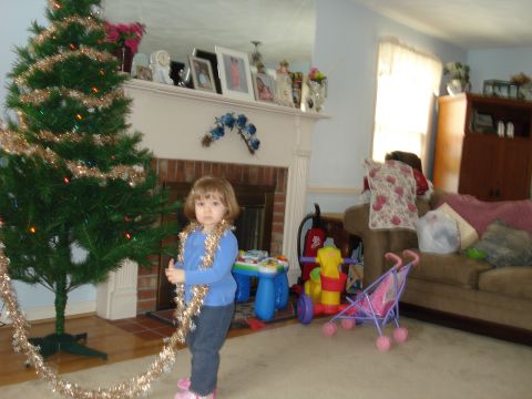 2000 Ford Crown Victoria - A child is in a living room decorated for Christmas, with a tree and fireplace visible.