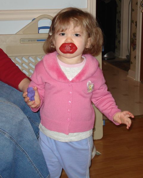 2000 Ford Crown Victoria - Toddler with a novelty pacifier stands indoors, holding a purple toy.
