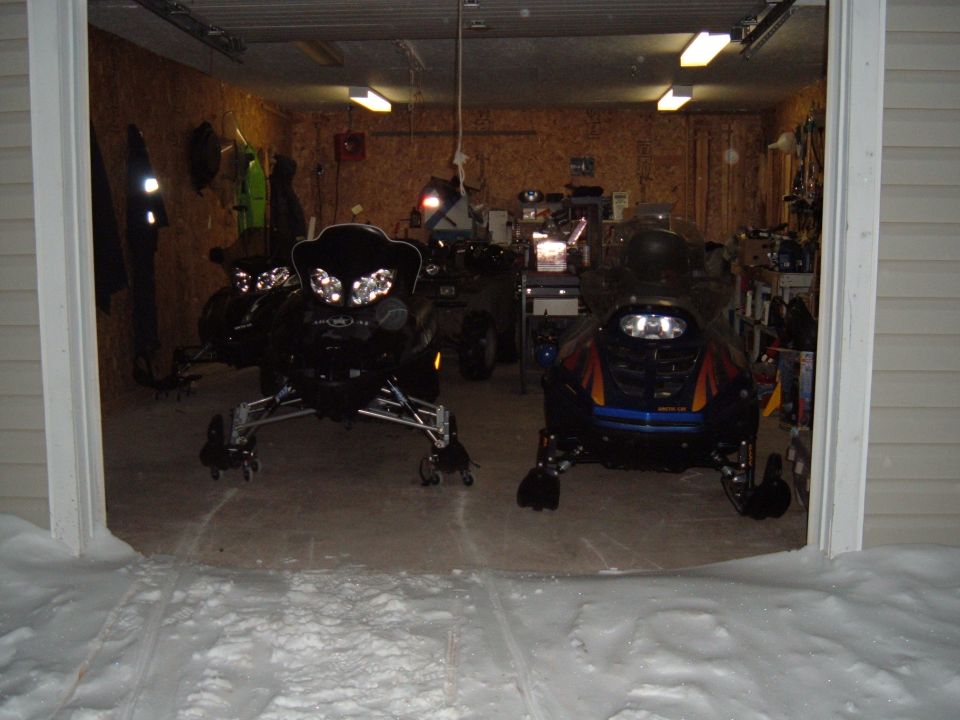 Two snowmobiles parked inside a garage.