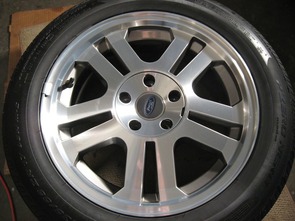 Silver Ford alloy wheel on a tire on the floor