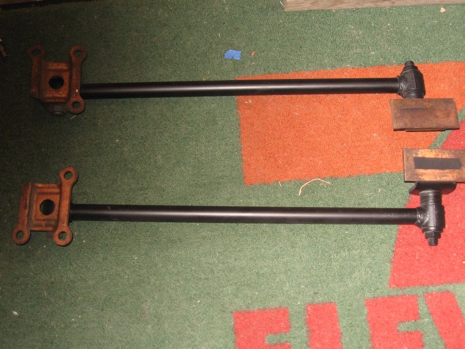 Two black metal rods with rusted brackets and wooden blocks