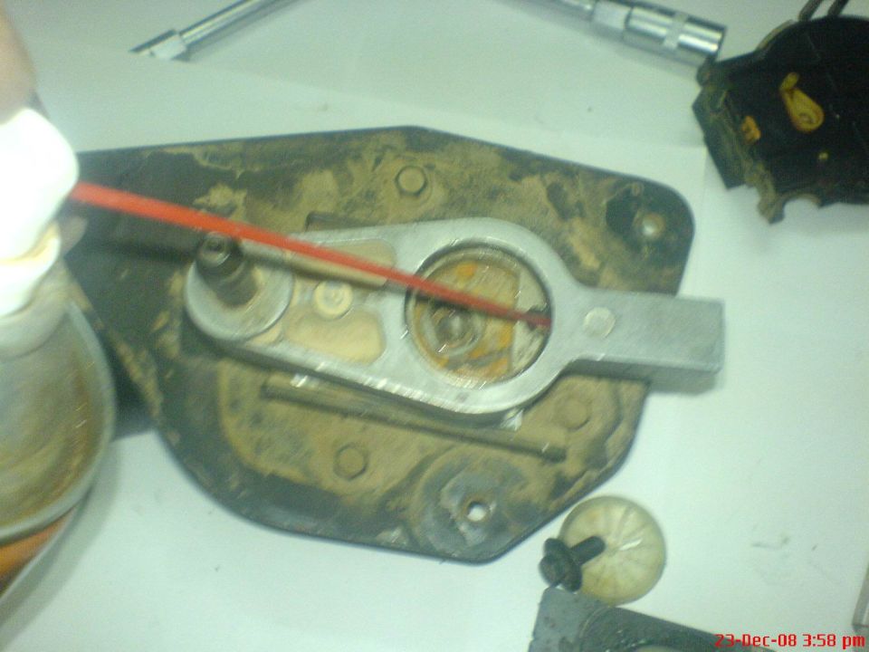 Aluminum pivot arm and dirty steel bracket disassembled on a white workbench