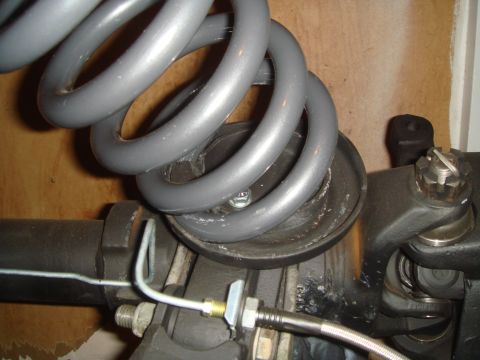 1992 Ford Bronco - A close-up view shows the suspension components of a vehicle, including a gray coil spring resting on a black spring seat, attached to a da…