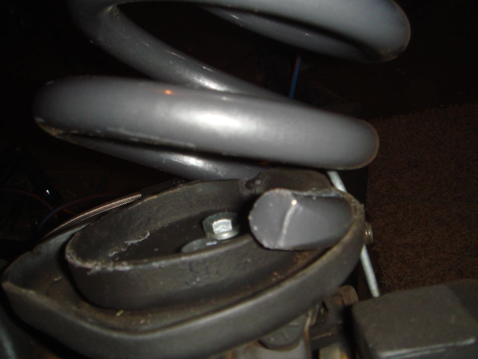 Close-up of a gray coil spring on a black mount with a bolt.