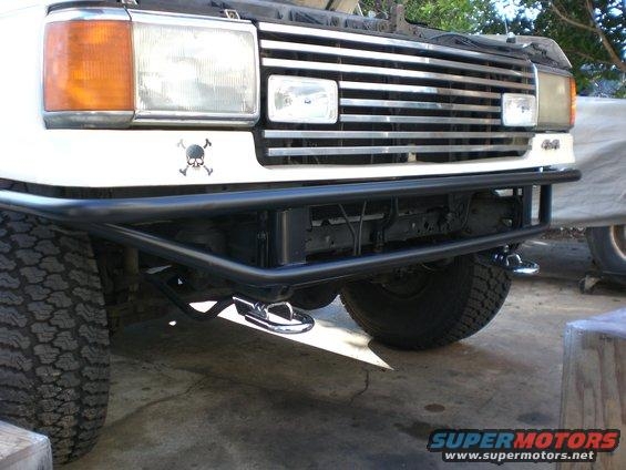 Black tube front bumper fitted to a white lifted 4x4 truck in a garage