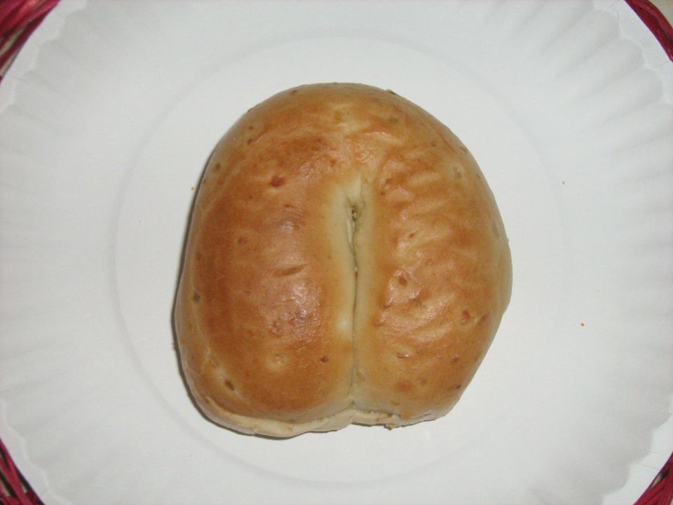 A baked bread roll on a white paper plate