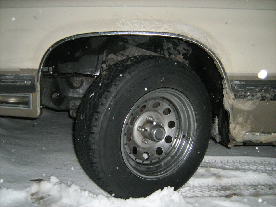 Close-up of a car's front wheel and fender in the snow.