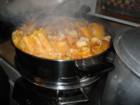 1986 Ford Bronco - A large steamer pot filled with tamales is steaming on a stovetop. The tamales are wrapped in corn husks and appear to be cooked.