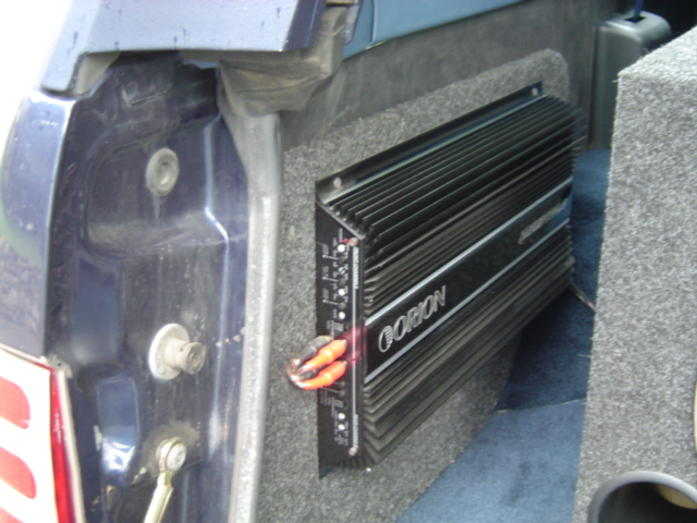 Orion amplifier mounted on gray carpeted panel in rear cargo area of dark blue Ford Bronco