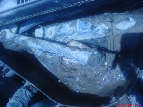 1992 Ford Crown Victoria - A close-up view of a heavily mud-covered mechanical linkage, likely part of a vehicle's windshield wiper system, with some blue paint visib…