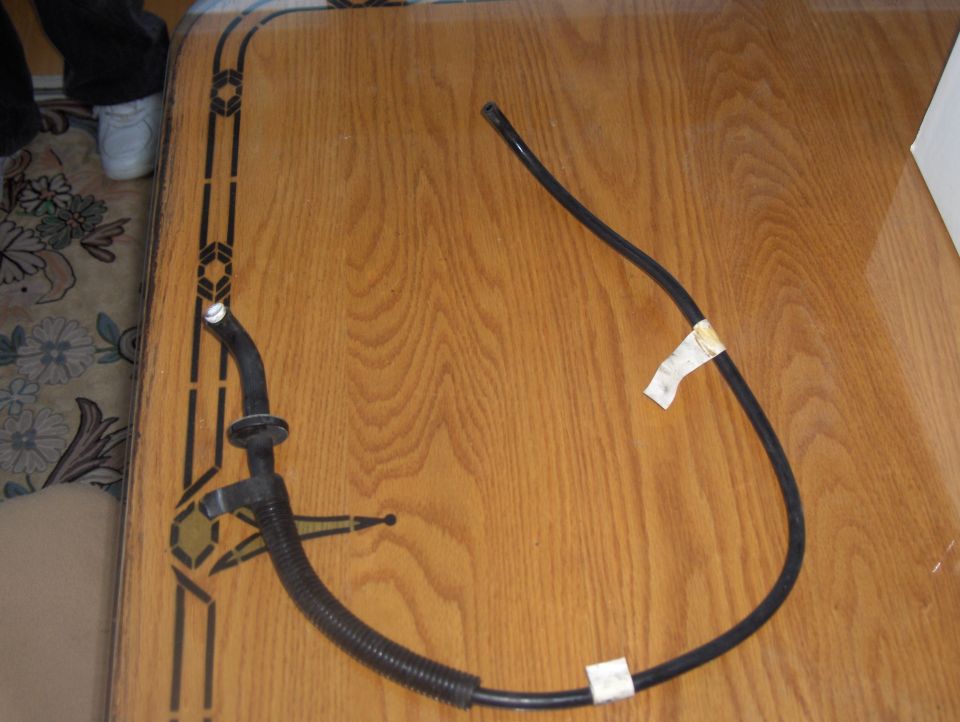 Black flexible hose with ribbed section and white tape markers on a wooden table