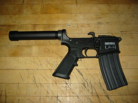 1996 Ford Bronco - A black AR-15 style rifle with a suppressor and a magazine is shown on a wooden surface. The receiver is marked with "INFIDEL" and Arabic s…