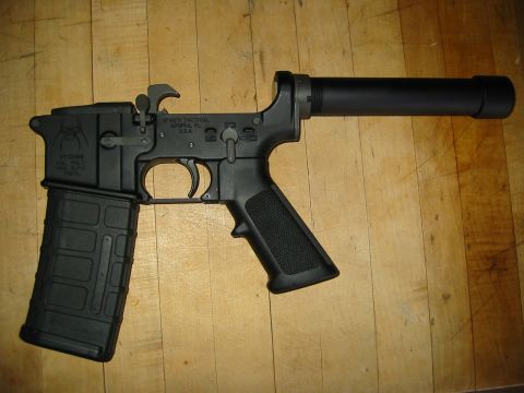 1996 Ford Bronco - A black AR-15 lower receiver with a magazine inserted and a suppressor attached is shown lying on a wooden surface.
