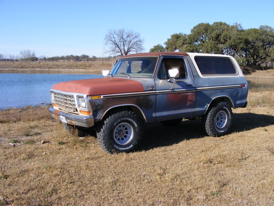 1979 Ford Bronco parked near water on a sunny day.
